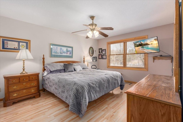 bedroom with ceiling fan, light wood-style flooring, and baseboards