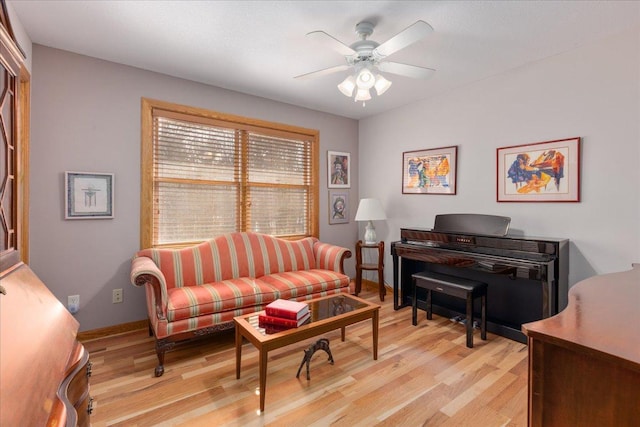 living room featuring ceiling fan, baseboards, and light wood-style floors