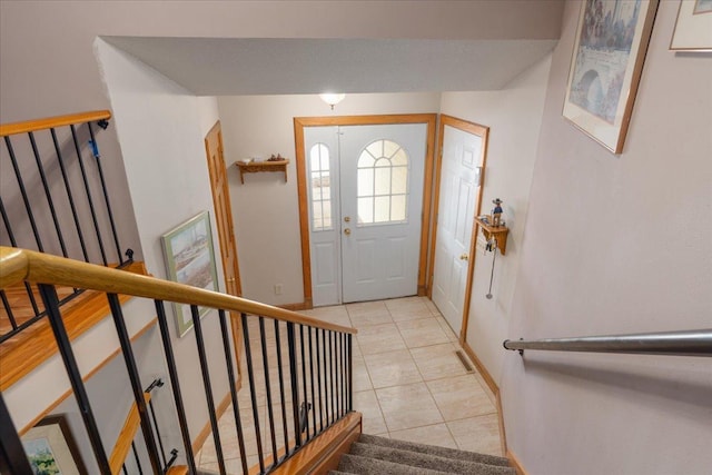 foyer entrance with stairway and light tile patterned flooring