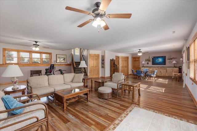 living room with stairs, baseboards, and light wood-style floors