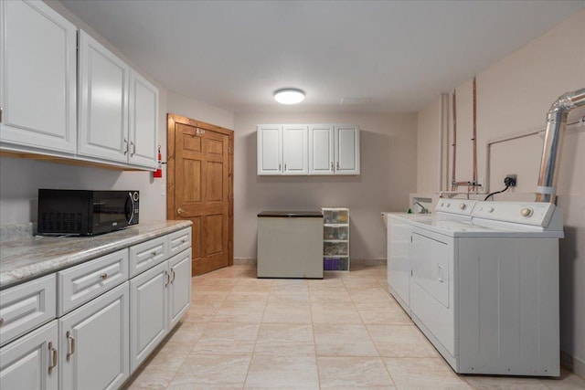 washroom featuring baseboards, cabinet space, and washing machine and clothes dryer