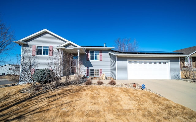 view of front of property with driveway, a garage, and solar panels