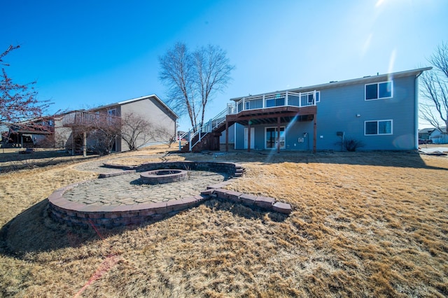 rear view of property featuring a fire pit, a deck, a patio area, and stairs