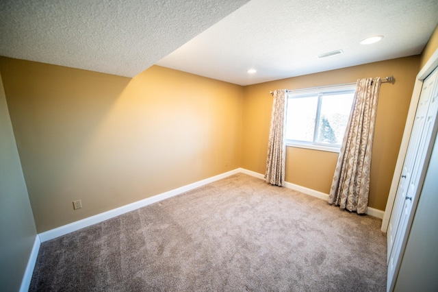 unfurnished room with carpet, recessed lighting, visible vents, a textured ceiling, and baseboards