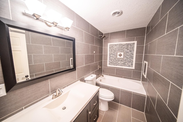 full bath featuring visible vents, toilet, tiled shower / bath, a textured ceiling, and tile walls