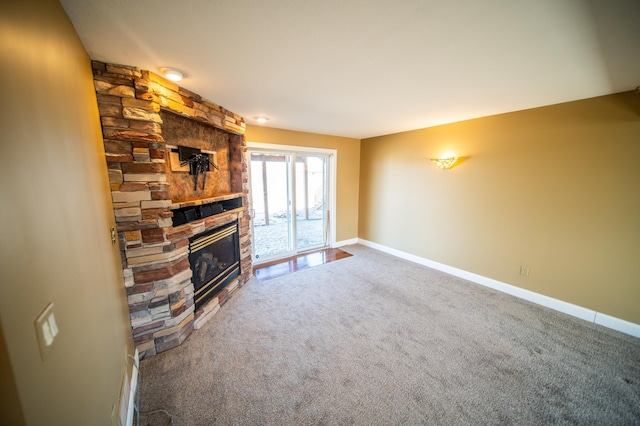 unfurnished living room featuring carpet, a stone fireplace, and baseboards