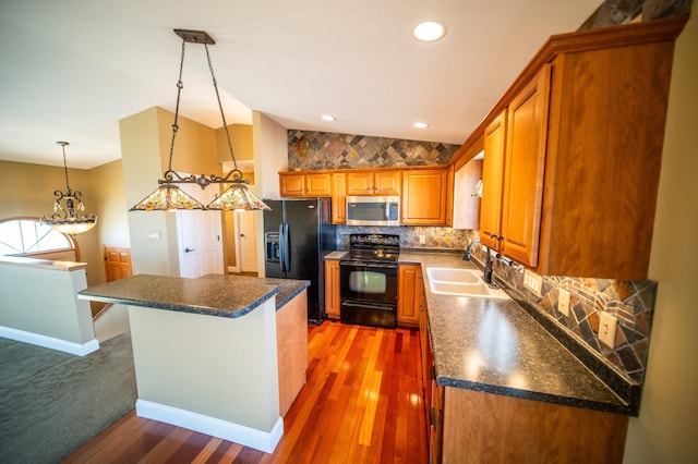 kitchen with lofted ceiling, black appliances, dark countertops, and a sink