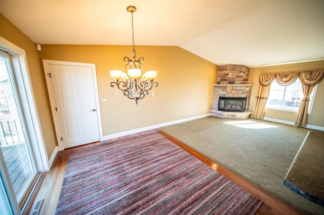 unfurnished living room with a fireplace, baseboards, vaulted ceiling, and wood finished floors