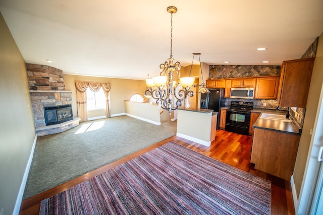 kitchen with electric range, stainless steel microwave, open floor plan, brown cabinets, and a stone fireplace