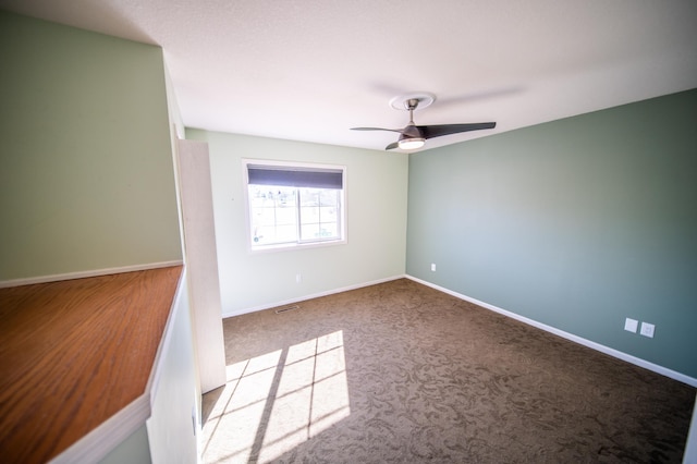 carpeted empty room with visible vents, ceiling fan, and baseboards