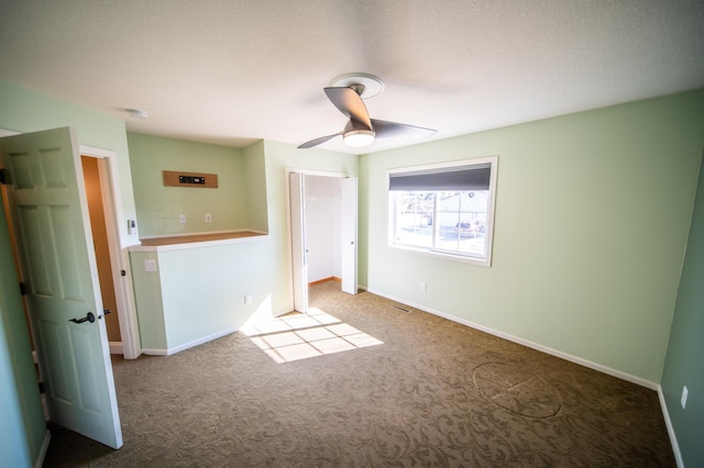 spare room with carpet floors, ceiling fan, and baseboards