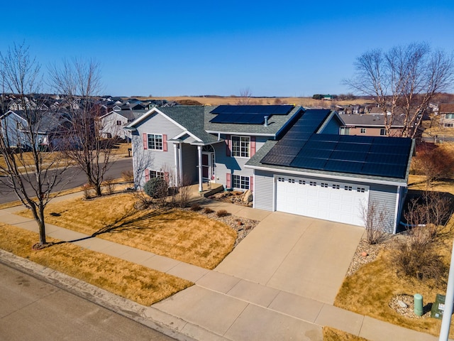 traditional-style house with driveway, a garage, a shingled roof, solar panels, and a residential view