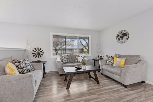 living area with baseboards and wood finished floors