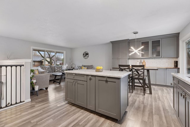 kitchen featuring light wood-type flooring, gray cabinets, and backsplash