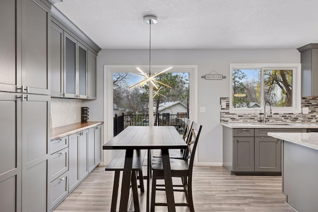 kitchen featuring backsplash, a chandelier, a sink, and gray cabinets