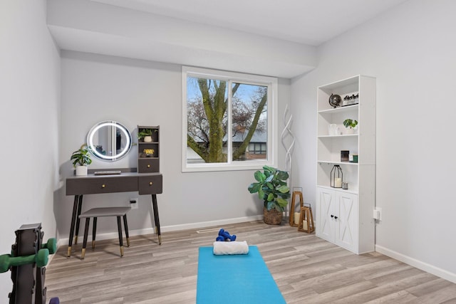 workout area featuring baseboards and light wood-type flooring
