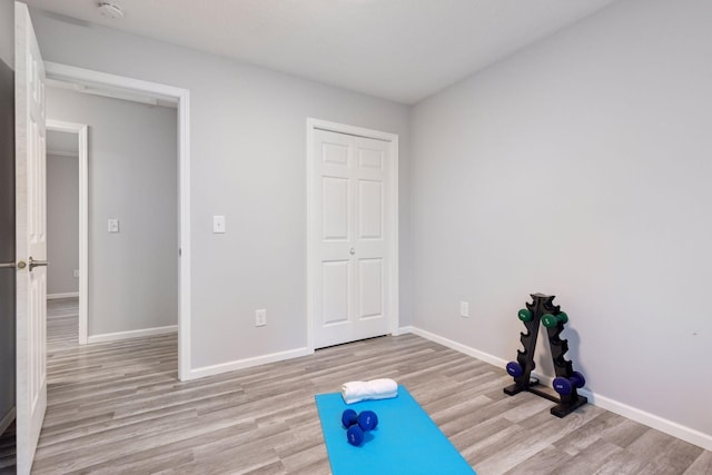 exercise room with baseboards and wood finished floors