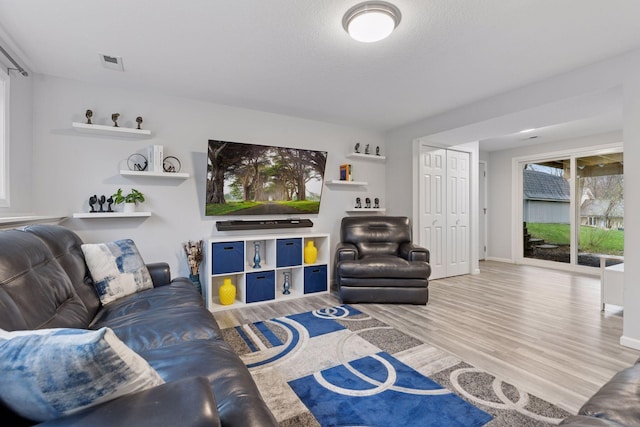 living area with baseboards, visible vents, and wood finished floors