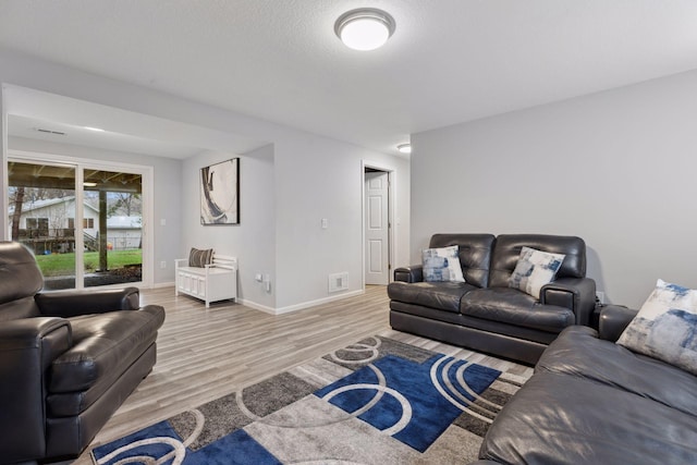 living area with light wood-style floors, baseboards, and visible vents
