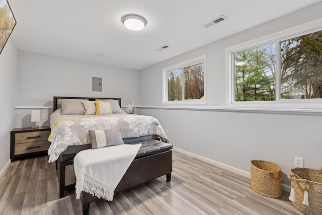 bedroom featuring baseboards, multiple windows, wood finished floors, and visible vents