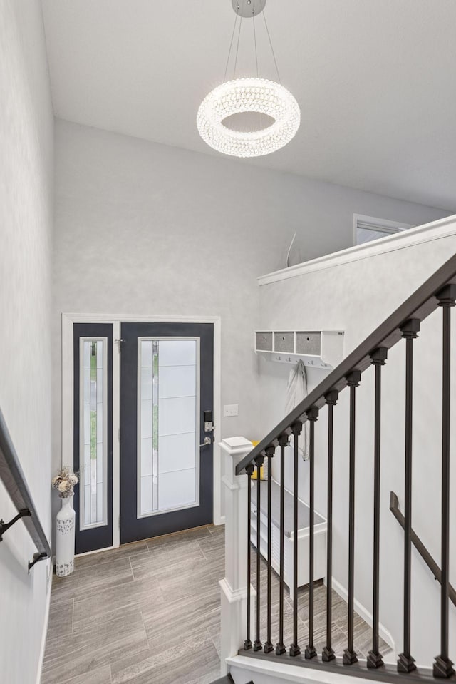 foyer entrance featuring baseboards, wood tiled floor, stairs, and a chandelier