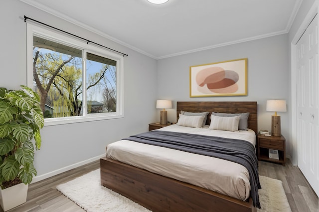 bedroom with baseboards, ornamental molding, wood finished floors, and a closet