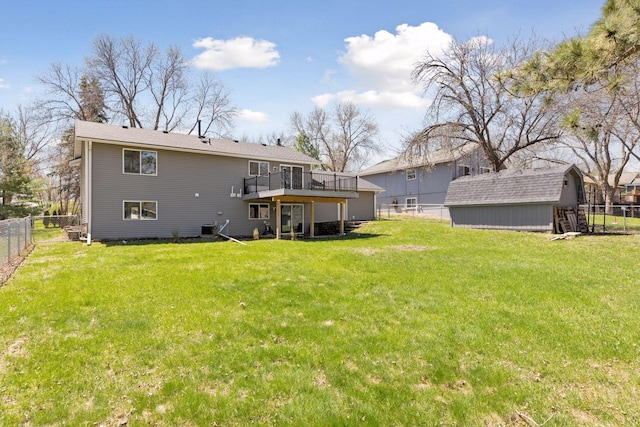 back of property featuring a lawn, a wooden deck, an outdoor structure, a fenced backyard, and a shed