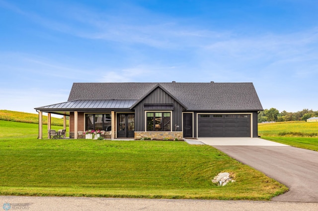 view of front of property with a garage, driveway, a shingled roof, metal roof, and a front lawn