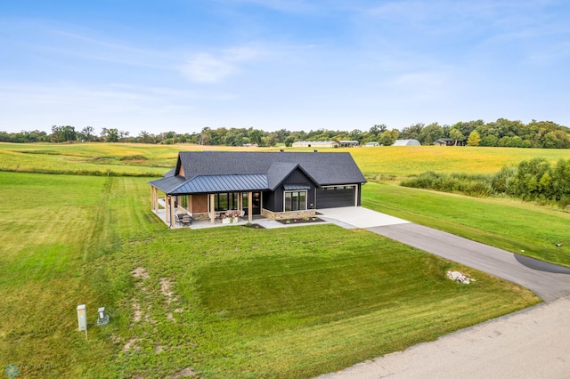 view of front of home featuring concrete driveway, an attached garage, a standing seam roof, metal roof, and a front lawn