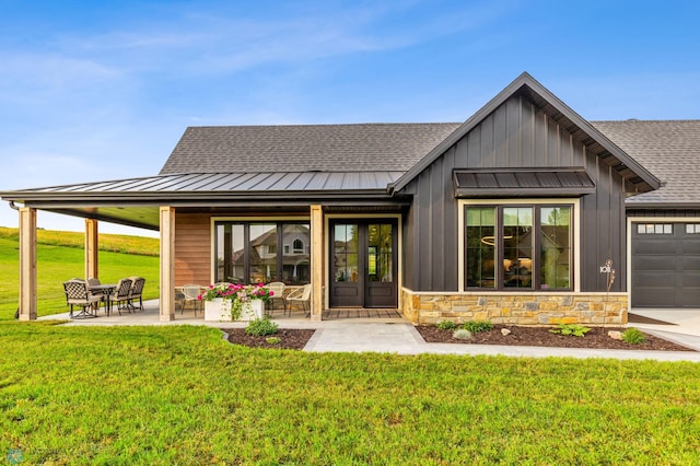 exterior space with a shingled roof, stone siding, metal roof, a standing seam roof, and a yard