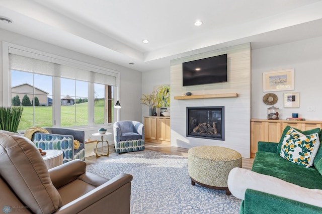 living area featuring a large fireplace, wood finished floors, and recessed lighting