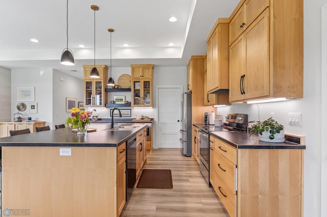 kitchen with stainless steel appliances, dark countertops, a sink, and light wood-style flooring