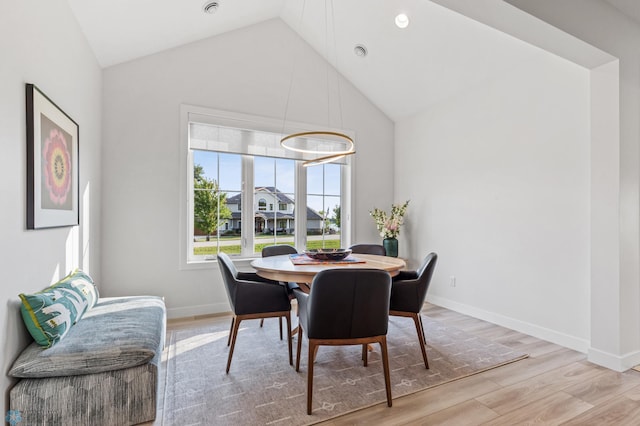 dining area with lofted ceiling, baseboards, and wood finished floors