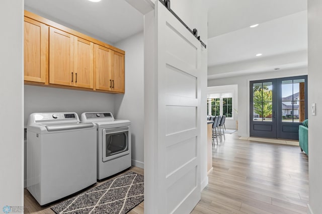 laundry room featuring cabinet space, a barn door, light wood-style floors, independent washer and dryer, and baseboards