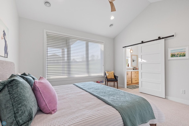 bedroom with lofted ceiling, light colored carpet, a barn door, ensuite bath, and baseboards