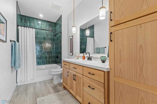 full bath featuring toilet, wood finished floors, visible vents, vanity, and shower / tub combo with curtain