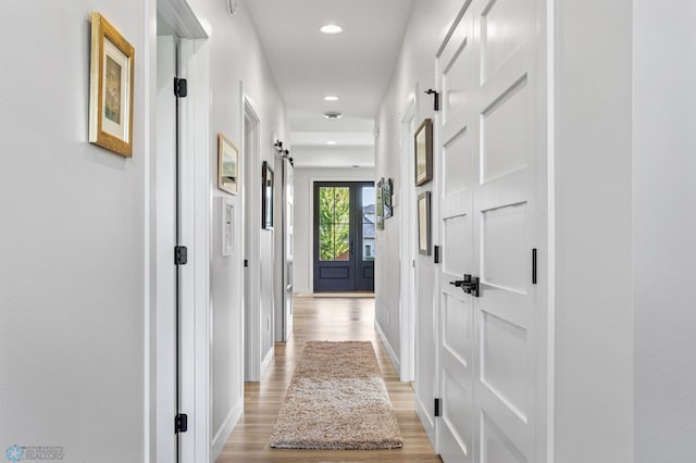 hallway featuring light wood-type flooring, baseboards, and recessed lighting