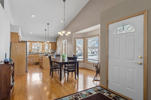 dining space featuring a chandelier, high vaulted ceiling, recessed lighting, baseboards, and light wood finished floors