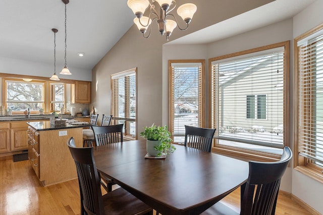 dining room featuring lofted ceiling, light wood finished floors, and an inviting chandelier