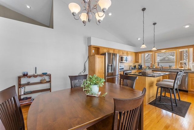 dining space with recessed lighting, a notable chandelier, vaulted ceiling, and light wood finished floors