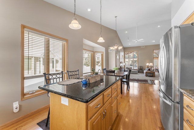 kitchen featuring open floor plan, light wood-type flooring, freestanding refrigerator, a center island, and a kitchen bar