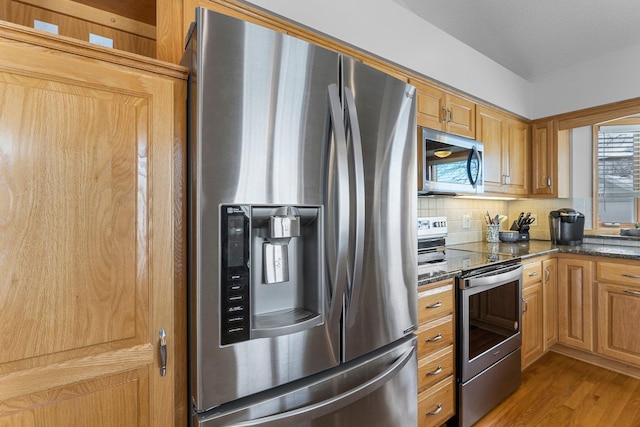 kitchen featuring stainless steel appliances, decorative backsplash, and wood finished floors