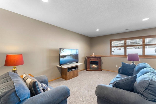 living room featuring light carpet, a lit fireplace, baseboards, and a textured ceiling