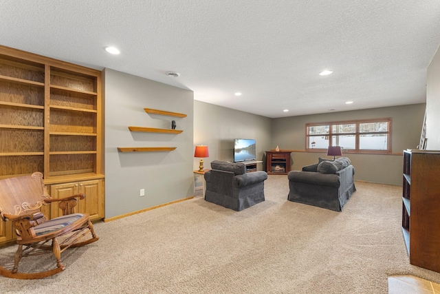 living area with a lit fireplace, carpet flooring, a textured ceiling, and baseboards