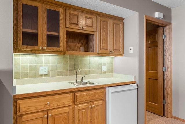 kitchen featuring glass insert cabinets, light countertops, dishwasher, and a sink