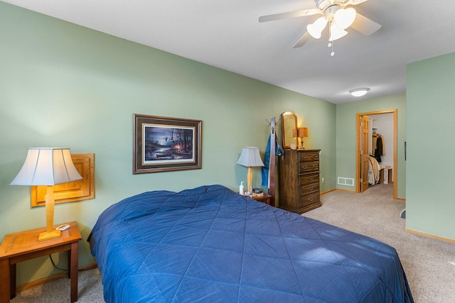 carpeted bedroom featuring ceiling fan, baseboards, visible vents, and a walk in closet