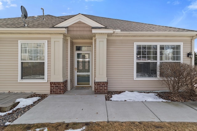 property entrance with brick siding and a shingled roof