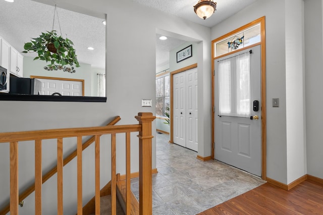 entrance foyer with recessed lighting, light wood-style floors, baseboards, and a textured ceiling