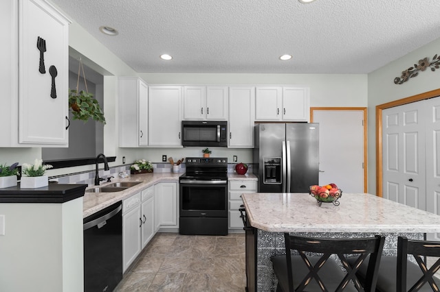 kitchen featuring a sink, black appliances, white cabinets, and recessed lighting