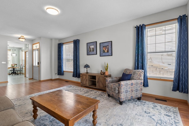 living room featuring visible vents, plenty of natural light, and wood finished floors